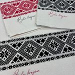 Kuhinjska krpa s potiskom belokranjskega vzorca v črni in rdeči barvi.